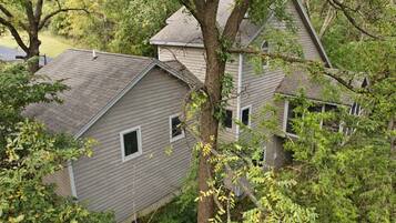 A house with a sloped roof, surrounded by dense foliage.