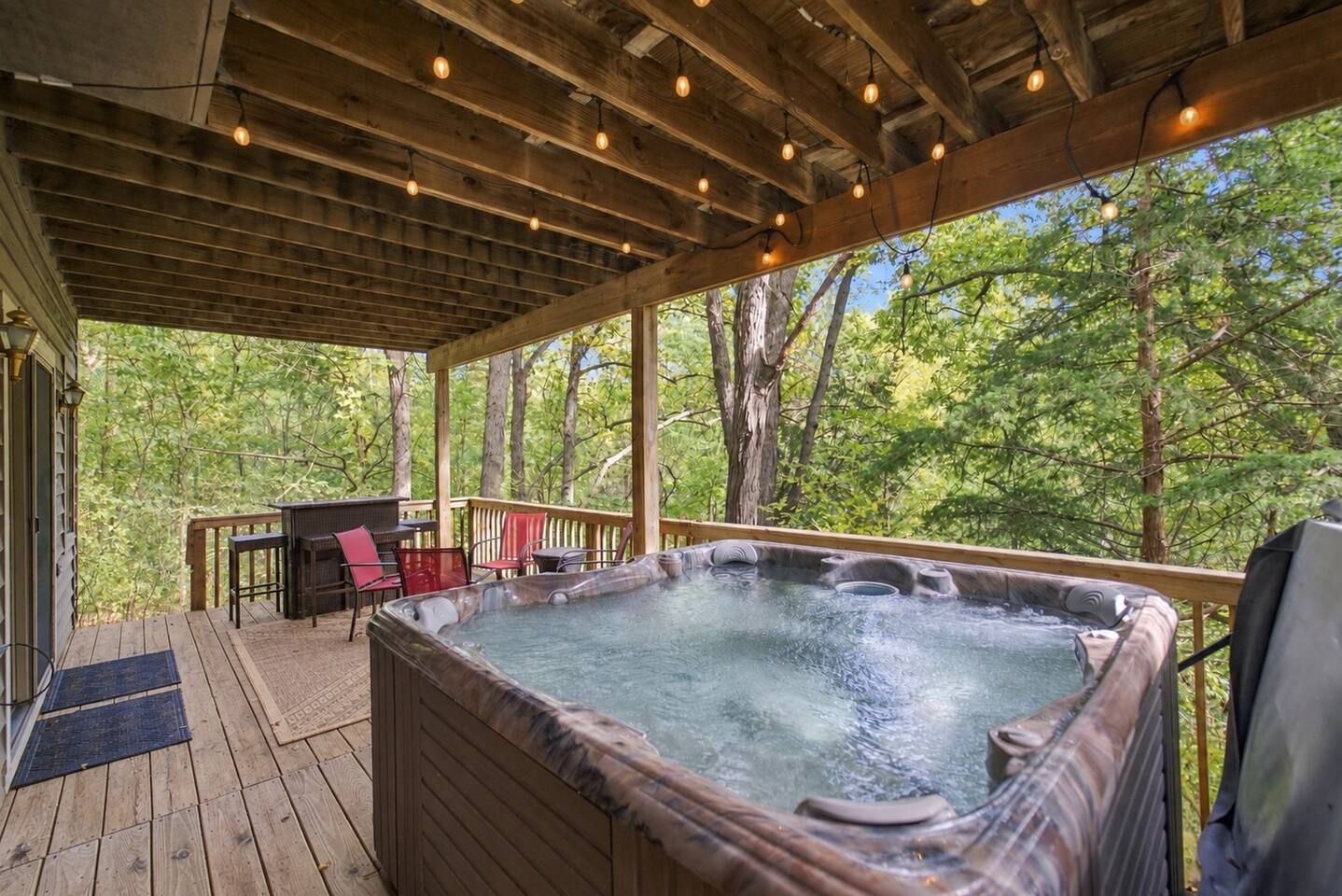Un jacuzzi en una terraza de madera con vista a árboles.