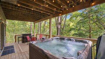 Un jacuzzi en una terraza de madera con vista a árboles.