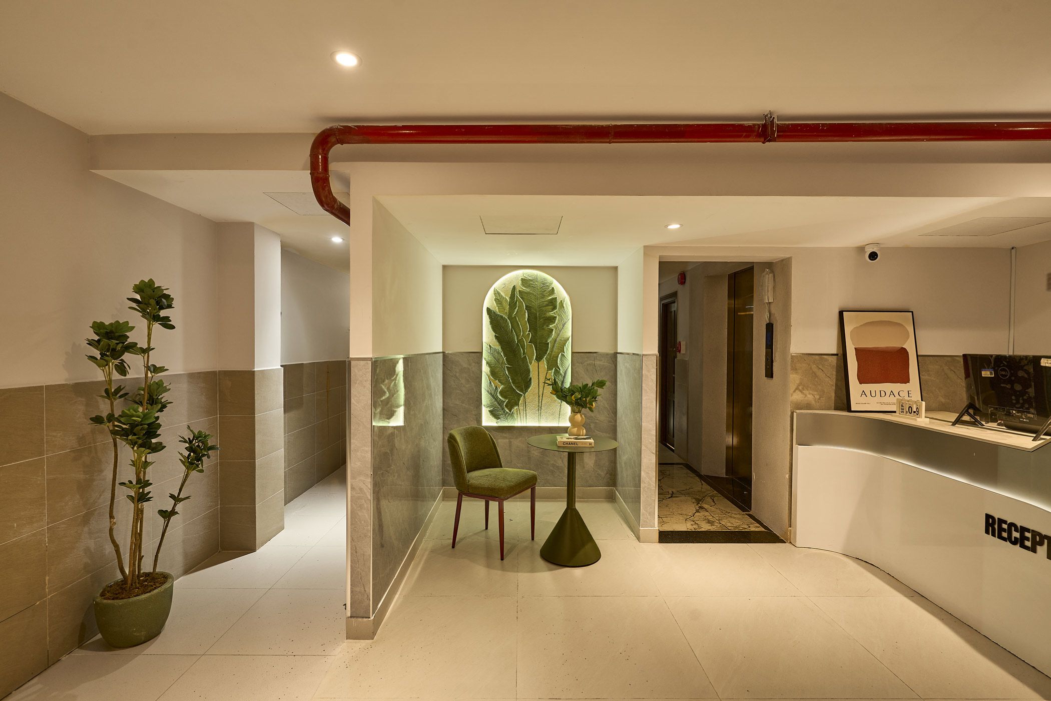 A reception area with a reception desk, a chair, a table, and a potted plant.
