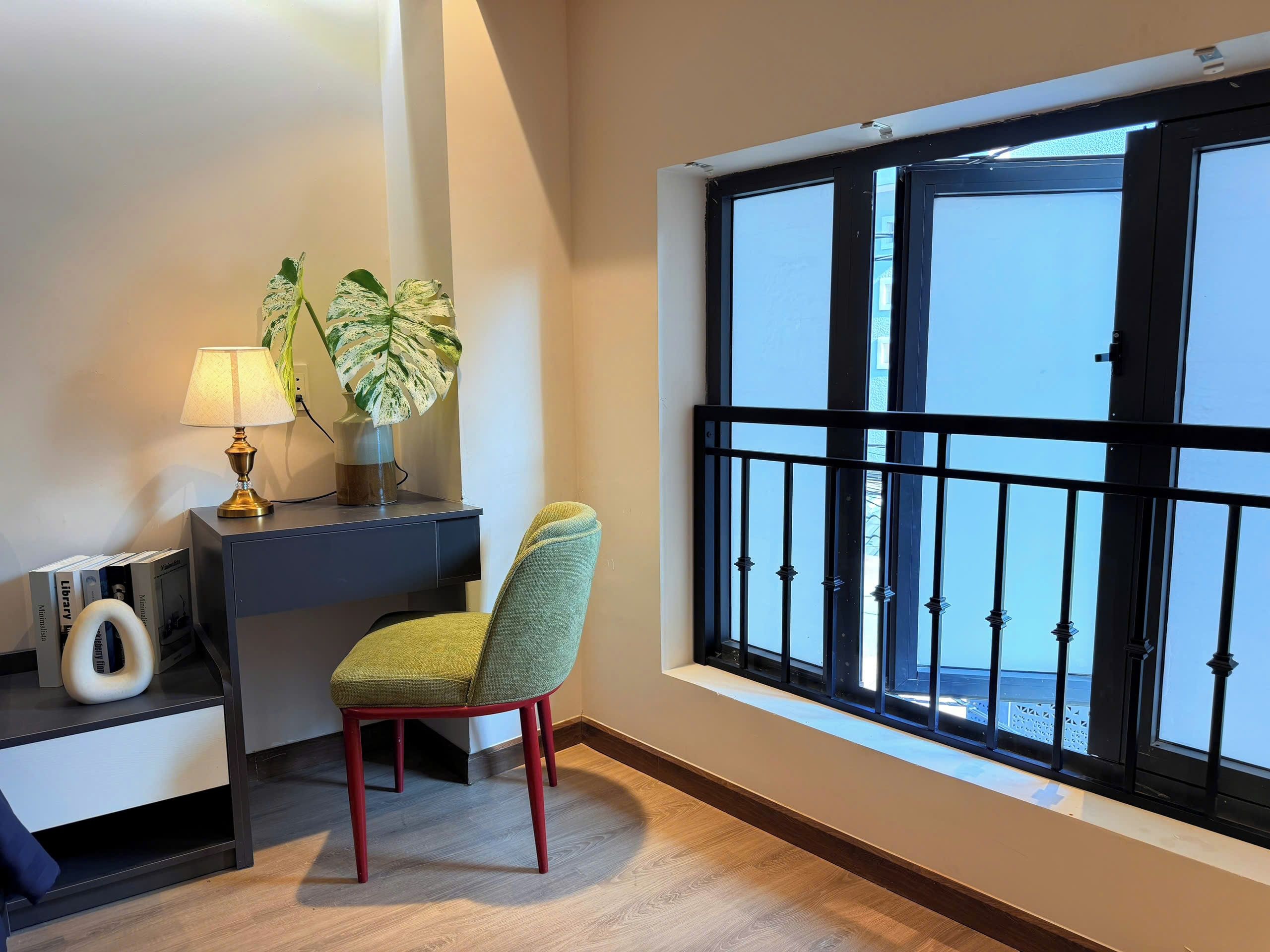 Ein Zimmer mit Schreibtisch, Stuhl, Blumentopf und einem Fenster mit Blick.