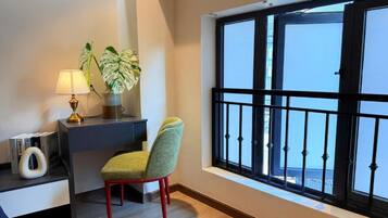 Une pièce comprenant un bureau, une chaise, une lampe et une grande fenêtre donnant sur un beau paysage.