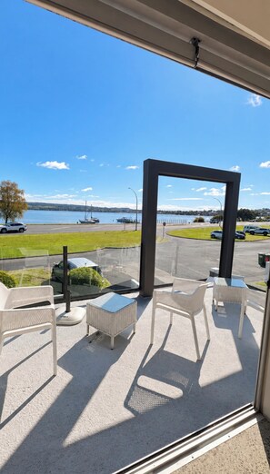 Ein Balkon mit Gartenmöbeln und Blick auf ein Gewässer und Boote.