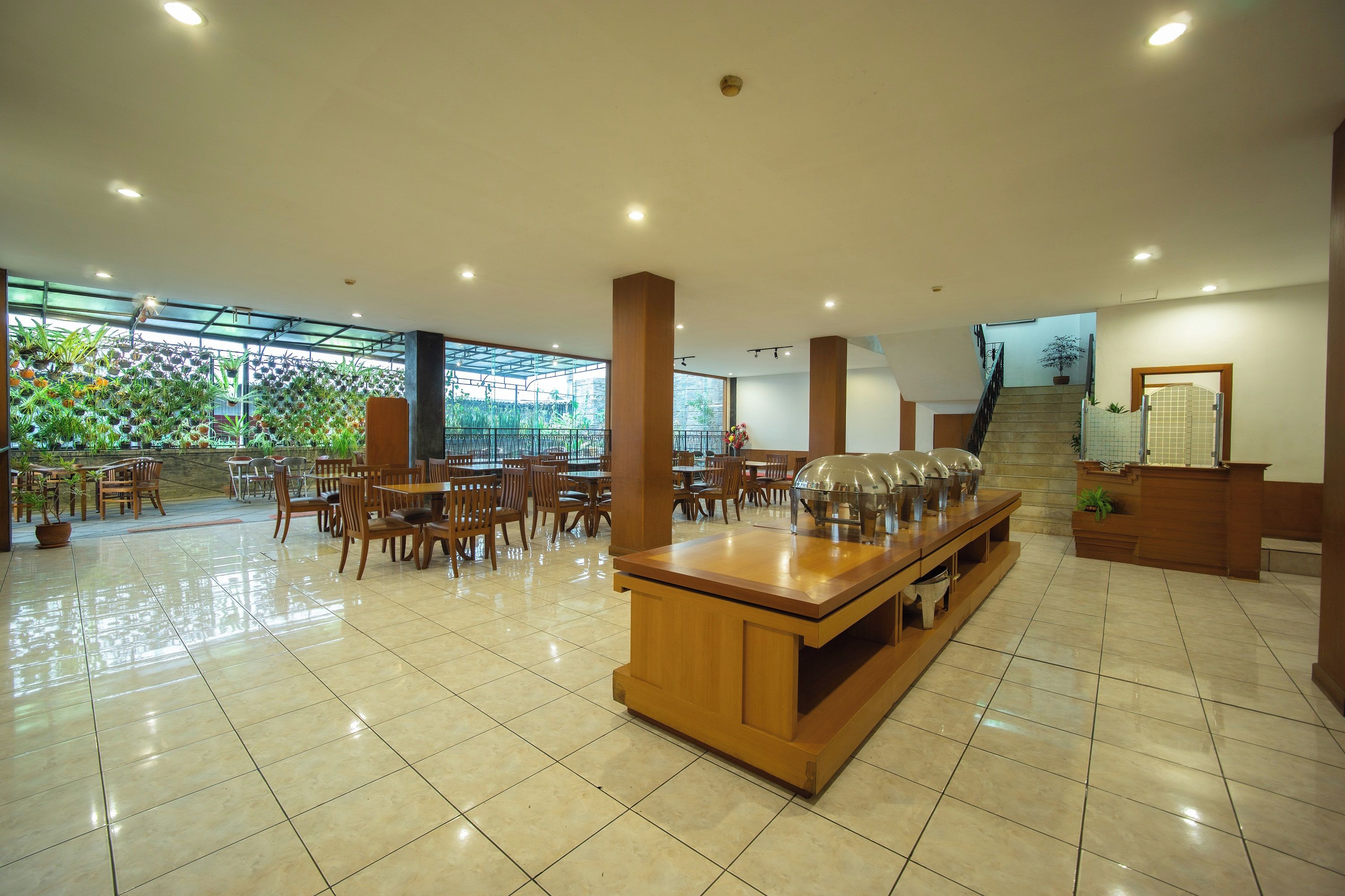 A spacious indoor area with a long counter, multiple tables, and chairs, and a staircase leading to an upper level.
