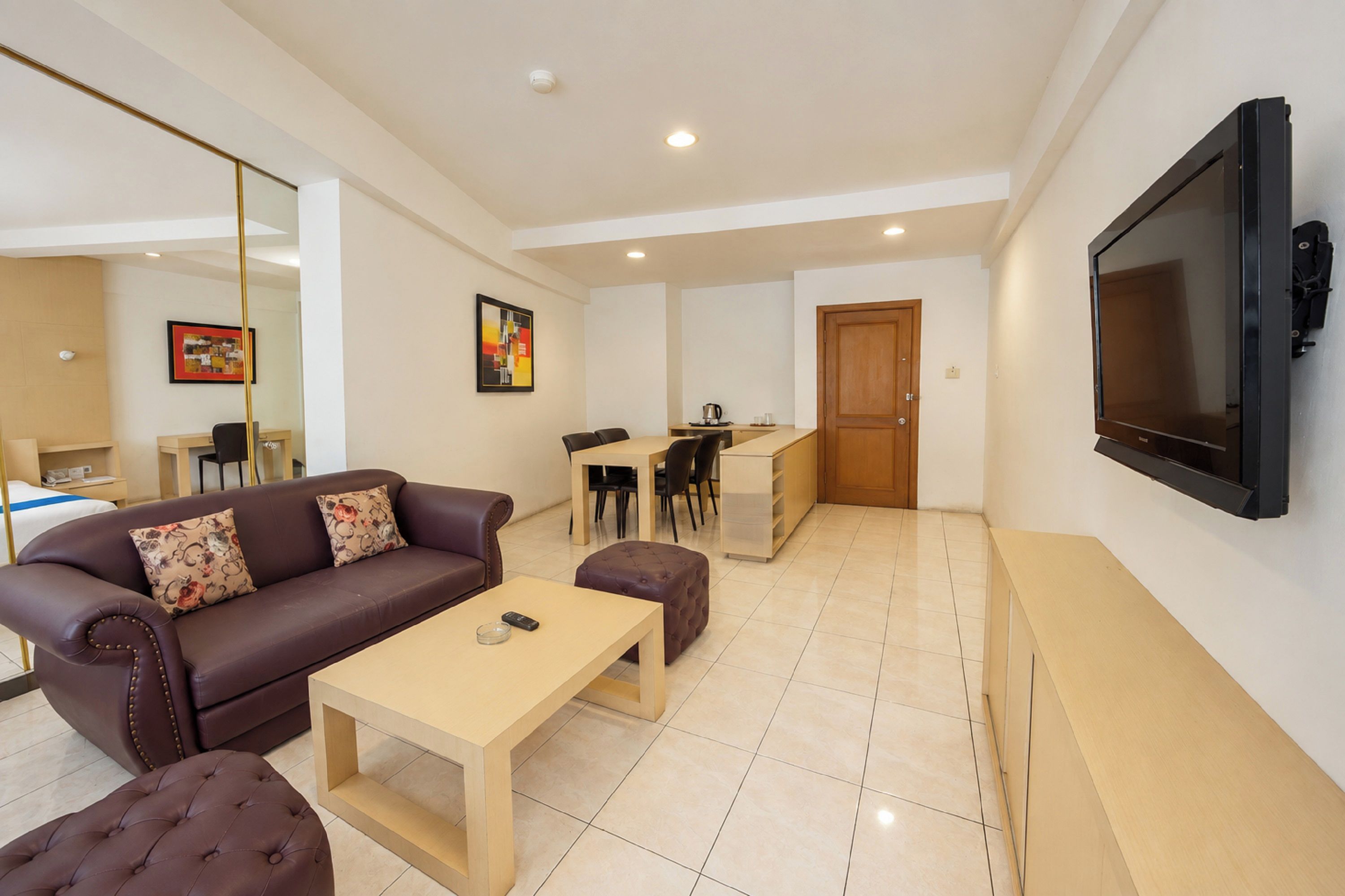 A modern living room with a sofa, ottoman, coffee table, and a TV mounted on the wall.