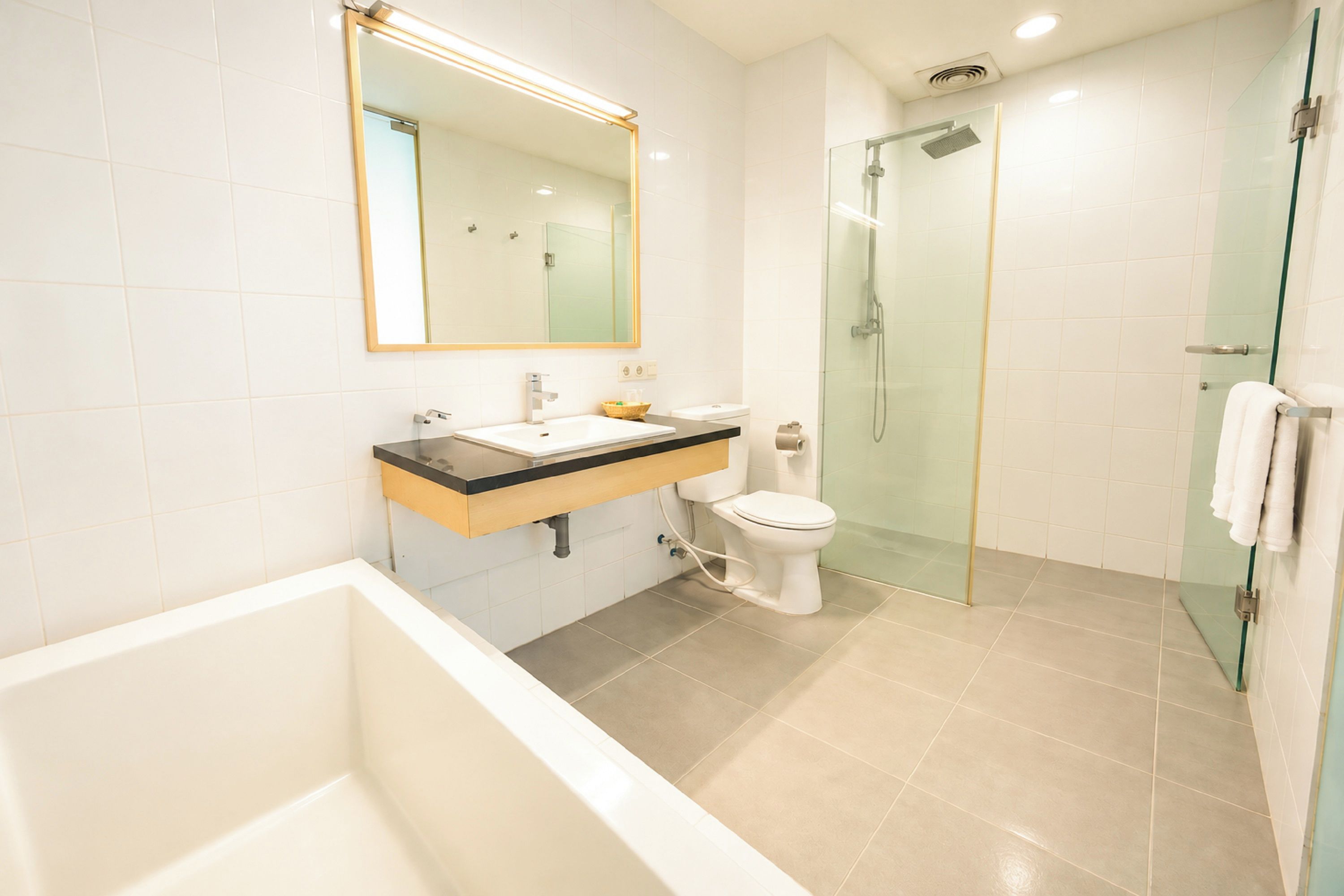 Un baño moderno con bañera, inodoro y zona de ducha con mampara de vidrio.
