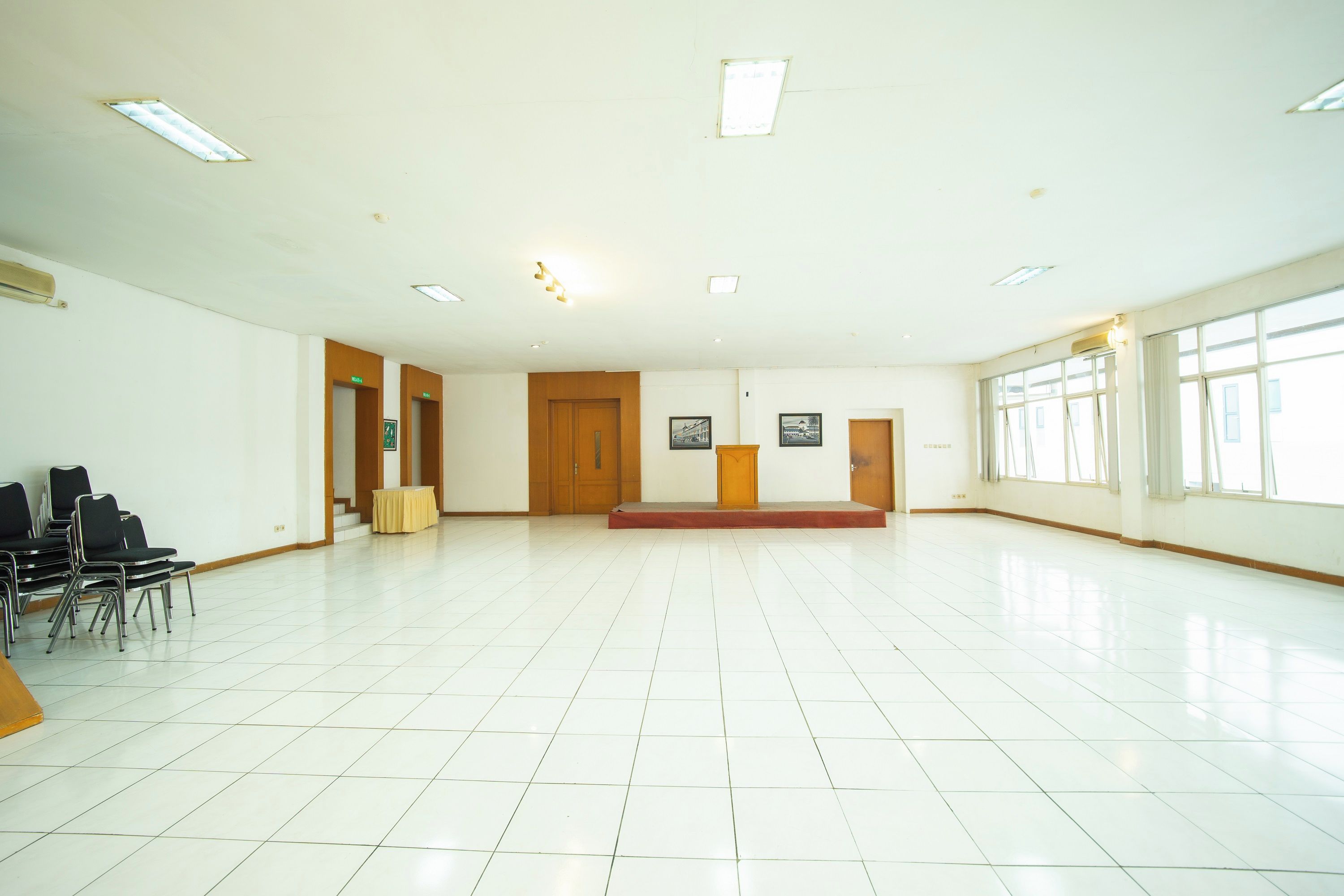A spacious room with a tiled floor, a wooden podium, and a bench.