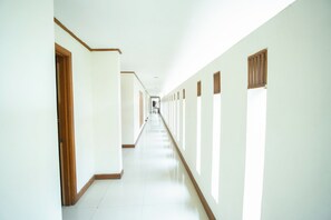 A long, narrow hallway with doors on both sides and windows on the right.