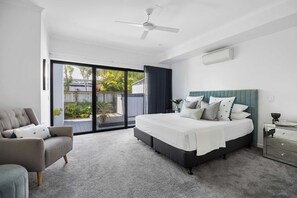 Ein Schlafzimmer mit einem Bett, einem Sessel, einem Deckenventilator und Blick ins Freie.