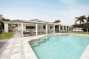 Uma casa moderna com varanda coberta, piscina e gramado bem cuidado.
