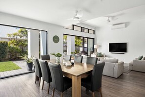 Ein modernes Wohnzimmer mit Essbereich, großen Fenstern und einem Flachbildfernseher.