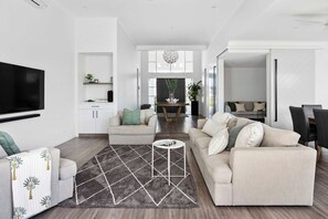 Een moderne woonkamer met een bank, een salontafel en een televisie aan de muur.