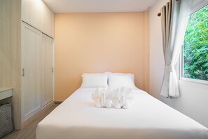 Habitació d'hotel amb llit, armari i finestra amb cortines.