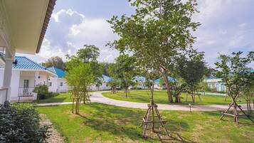 A residential area with a paved walkway, trees, and houses with blue roofs.