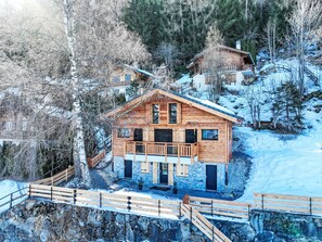 A wooden cabin with a balcony, surrounded by snow-covered trees and a rocky slope. - Byzance 6 by Interhome (Nendaz)