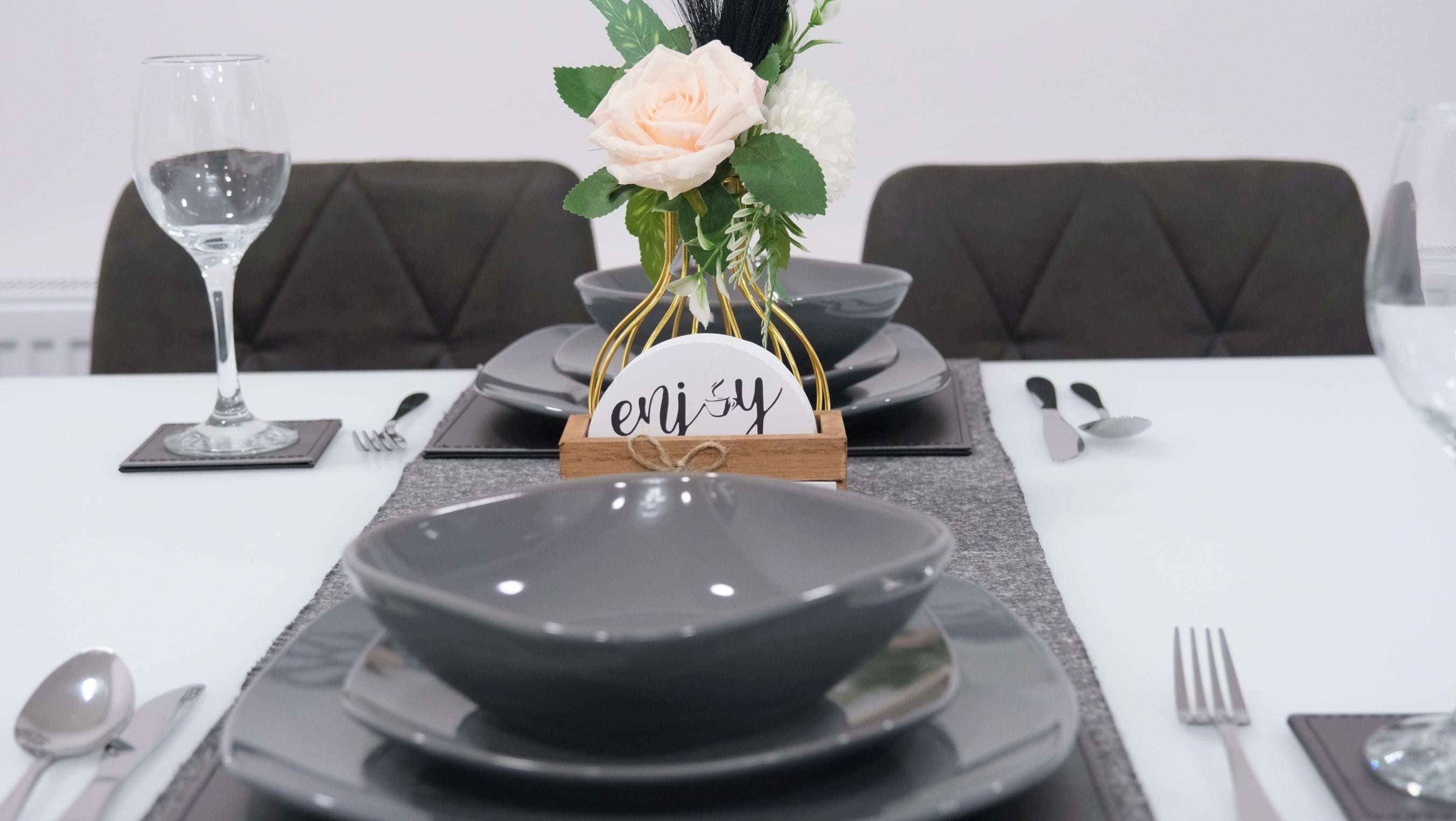 A dining table set with plates, bowls, cutlery, and a glass of water.