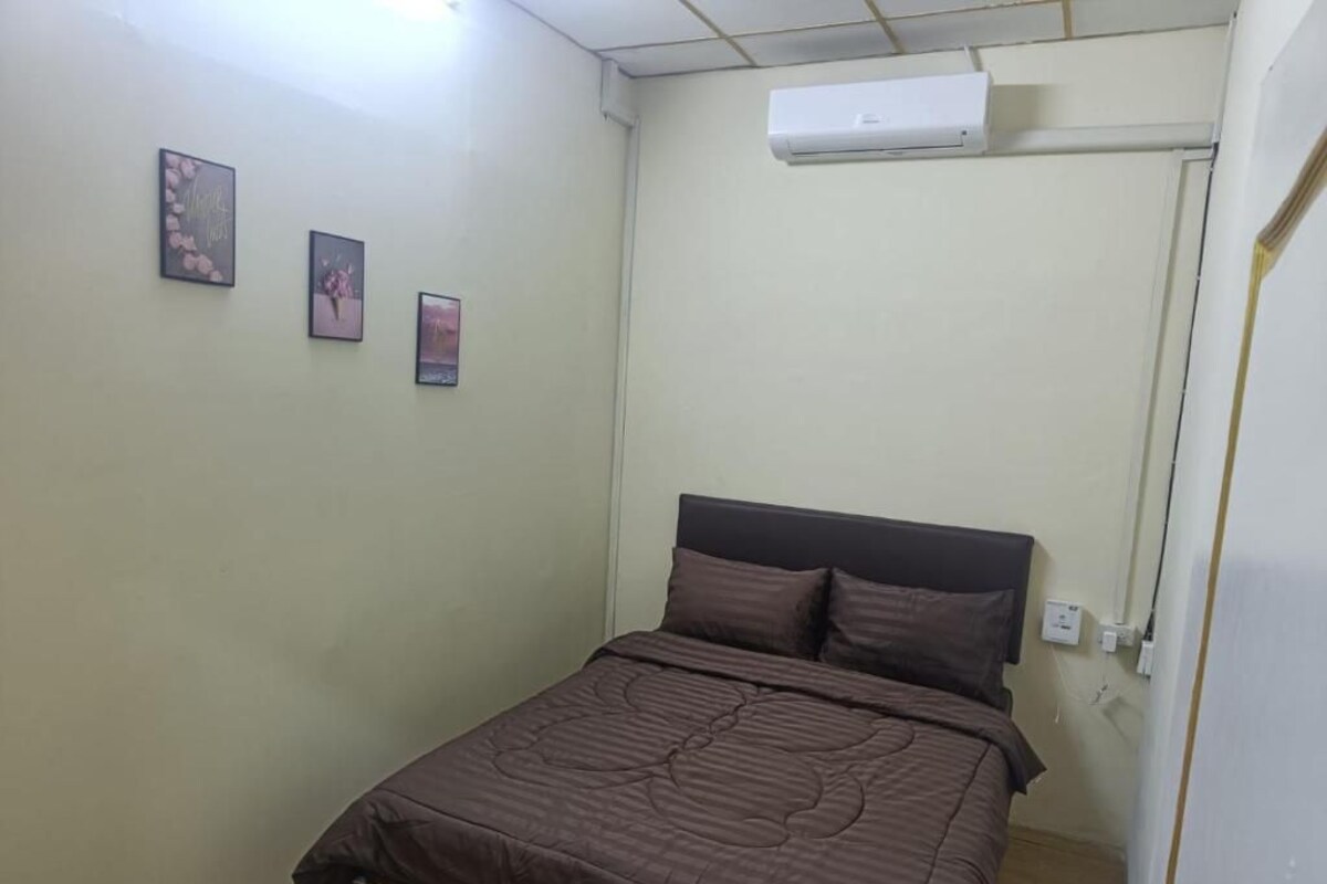 Quarto com cama, ar condicionado fixado na parede e três quadros emoldurados.