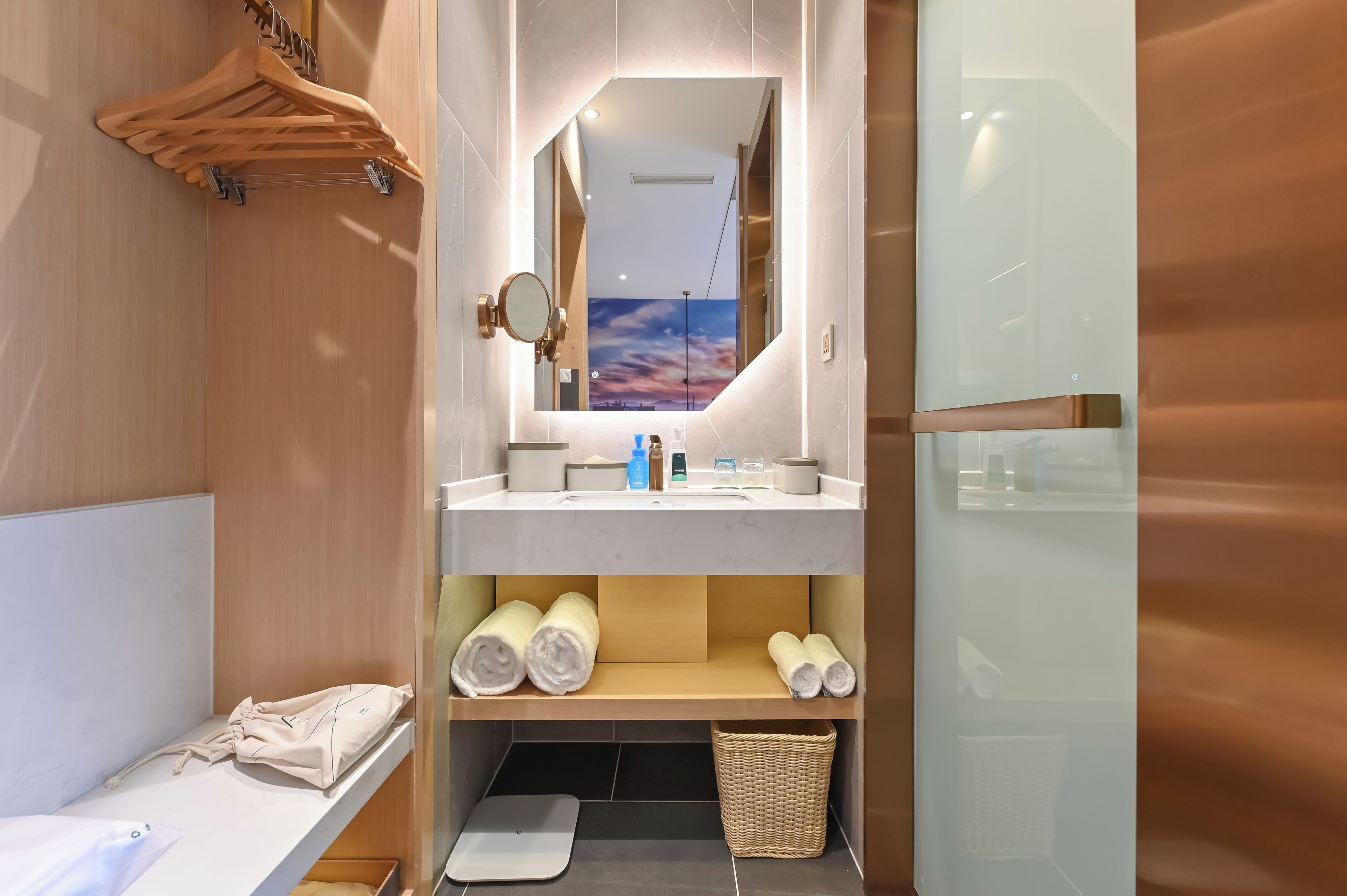 Un baño moderno con tocador de madera, un espejo, un lavamanos y una zona de ducha.