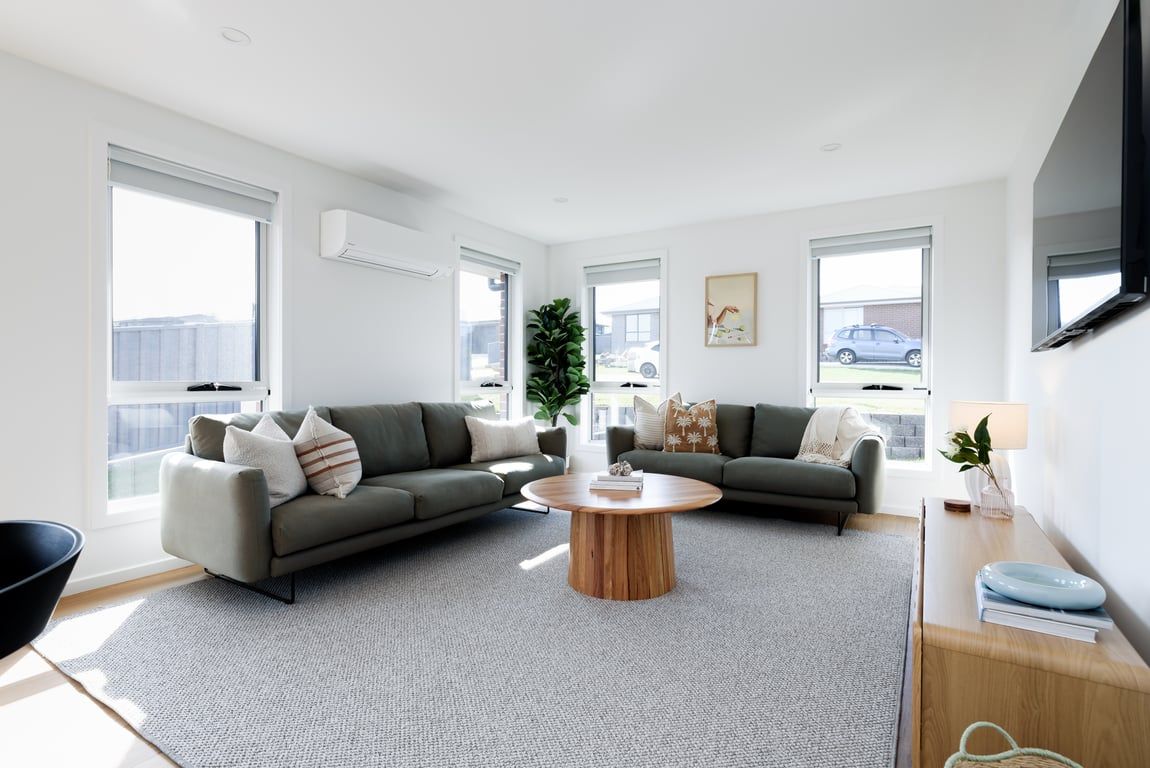 Un salon moderne avec deux canapés, une table basse et une grande fenêtre donnant sur l’extérieur.