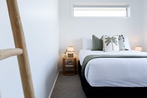 Ein Schlafzimmer mit einem Bett, Nachttischen, einem Fenster und einem Holzstuhl.