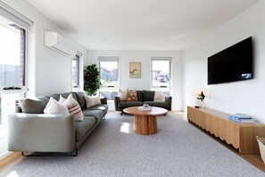 Ein modernes Wohnzimmer mit zwei Sofas, einem Couchtisch, einem Fernseher und einem großen Fenster.