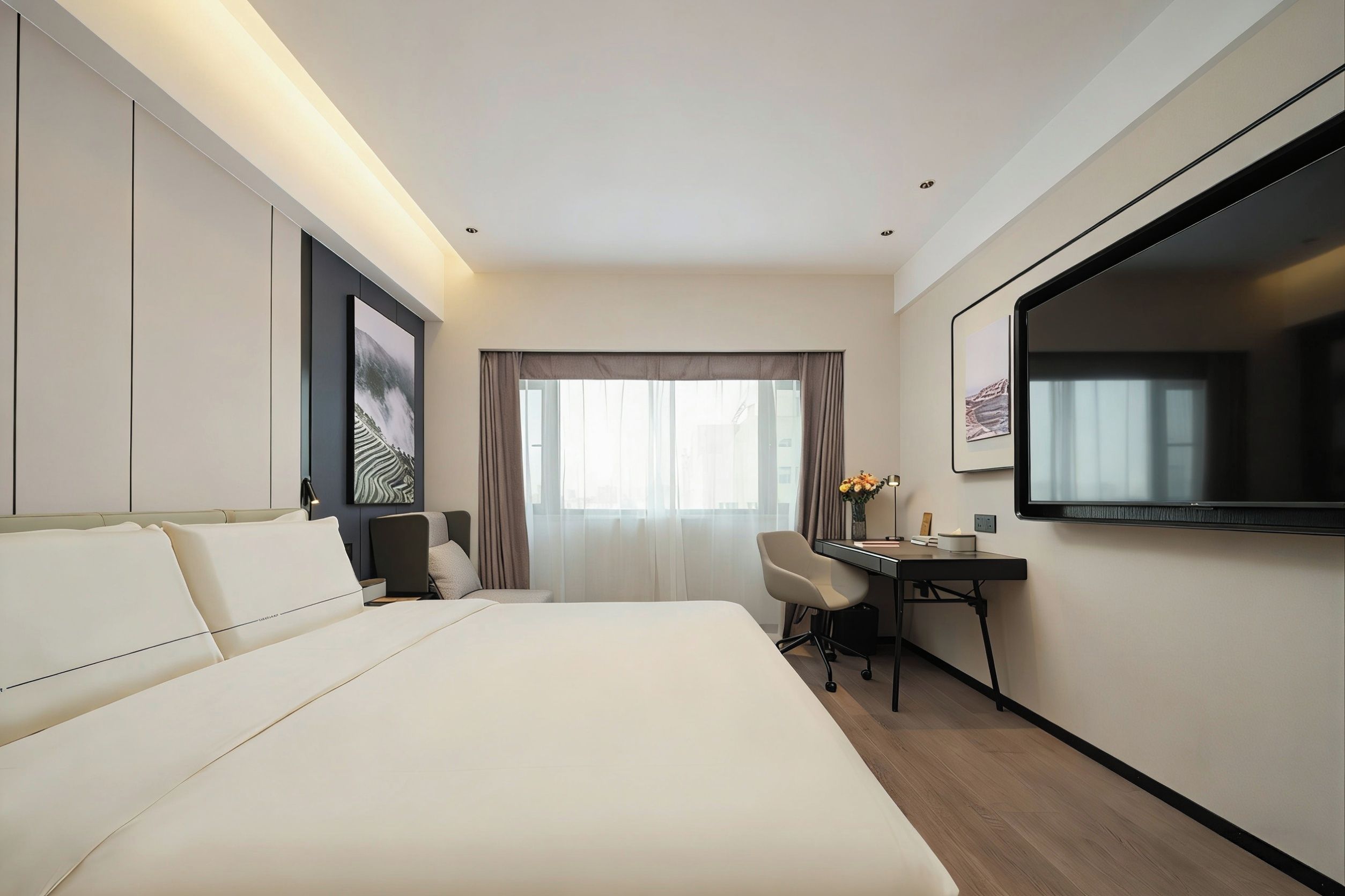 A hotel room with a large bed, a desk, a chair, a television, and a window with curtains.