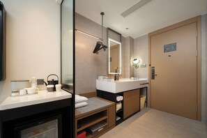 Un baño moderno con tocador, espejo, toallero y puerta con señal de salida de emergencia.