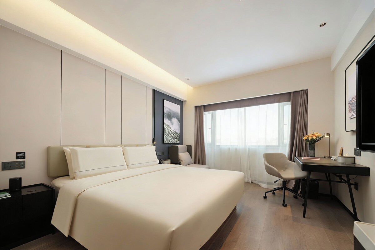 Una habitación de hotel con una cama grande, un escritorio y una silla.