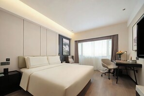 Una habitación de hotel con una cama grande, un escritorio y una silla.