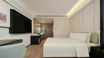 A hotel room with a bed, bedside table, TV, and a mirror.
