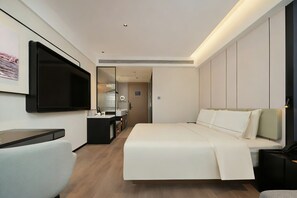 Una habitación de hotel con cama, mesita de noche, televisor y espejo.
