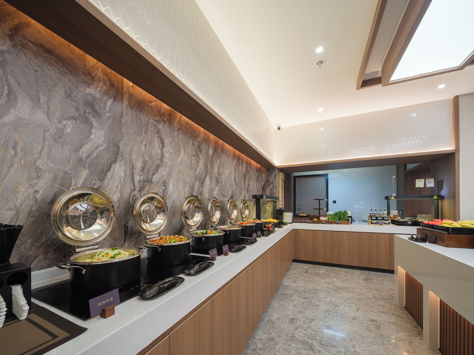 A modern buffet setup with multiple serving stations, a marble backsplash, and a clean, contemporary design.
