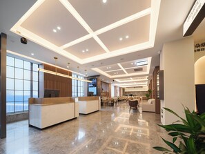 Un moderno vestíbulo de hotel con mostrador de recepción, zona de estar y un amplio ventanal con vistas.