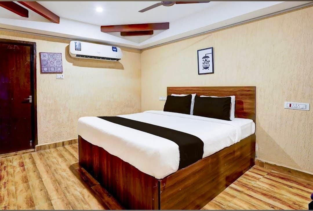 Un dormitorio con cama de madera, ventilador de techo, equipo de aire acondicionado y una puerta.