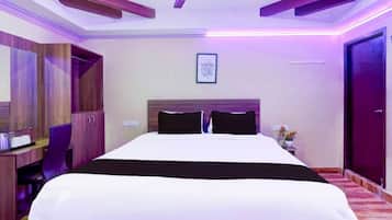 A hotel room with a bed, a desk, a chair, a ceiling fan, and a door.