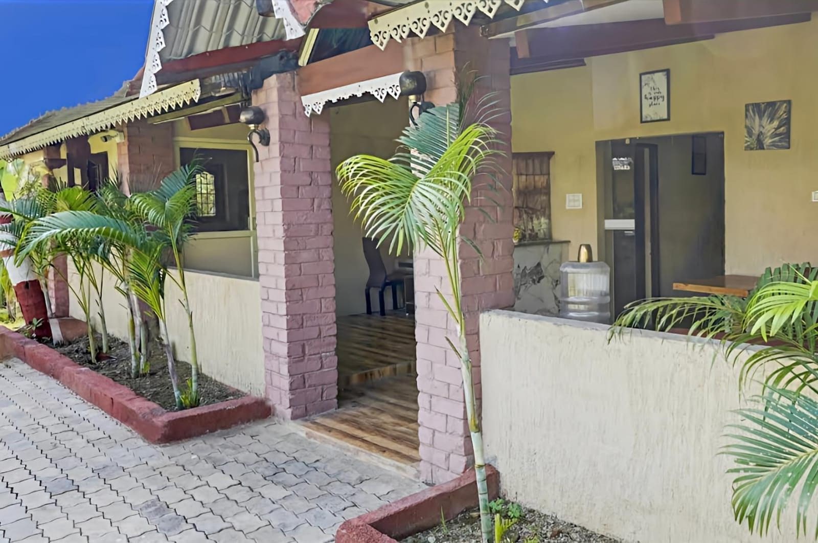 A building with a porch, potted plants, and a water dispenser.