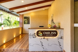 A reception desk with a marble top and a sign for OMR, INN RESORT.