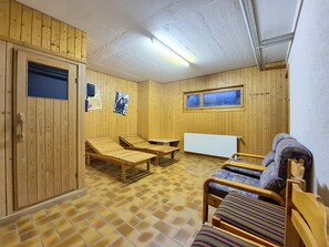 A sauna room with wooden walls, a tiled floor, and a window. There are benches and a table. - Domino C D-1 by Interhome (Nendaz)