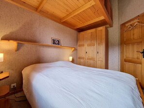 A bedroom with a large bed, wooden wardrobe, and a framed picture on the wall. - Domino C D-1 by Interhome (Nendaz)