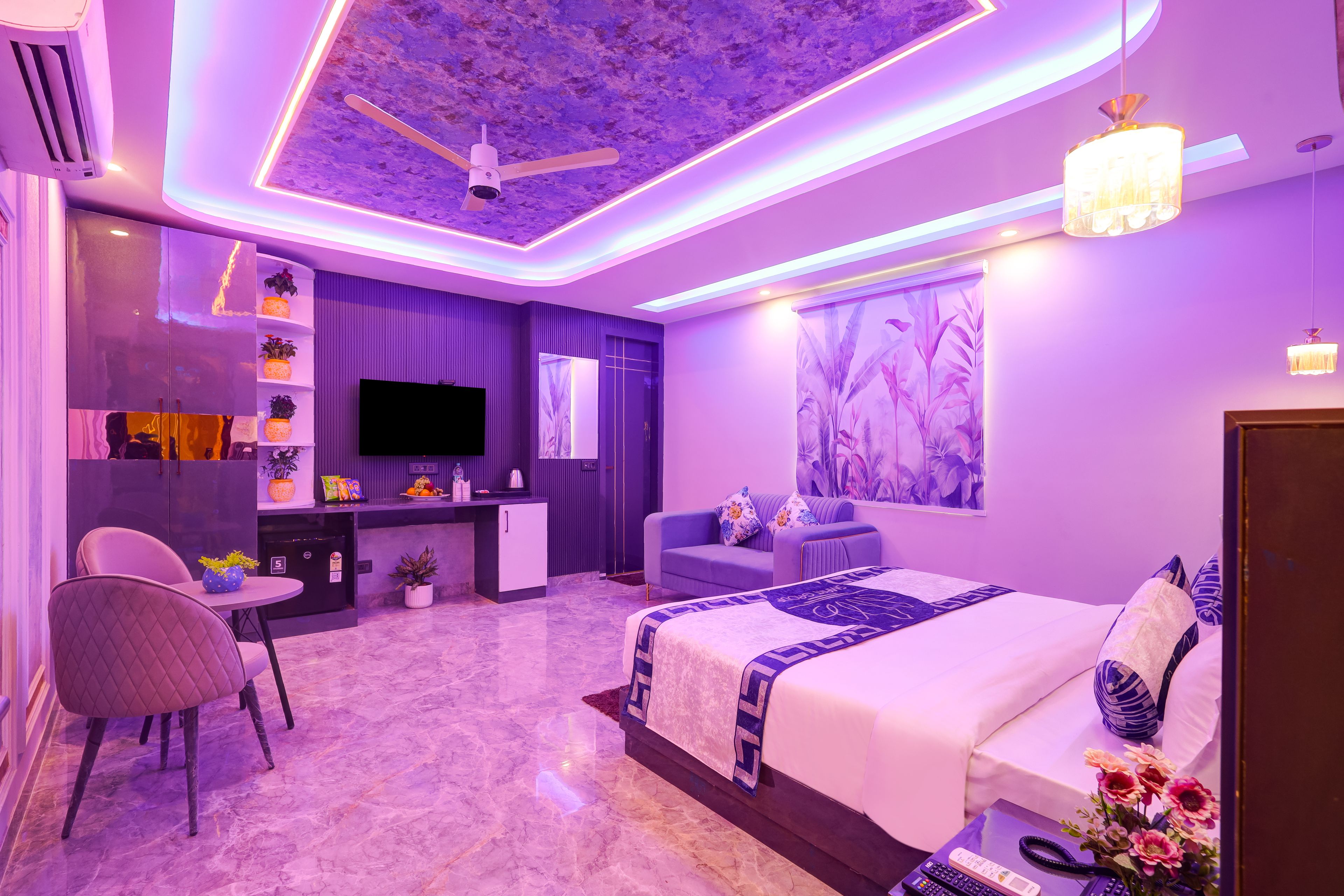 A modern bedroom with a bed, a desk, a chair, a television, and a ceiling fan.