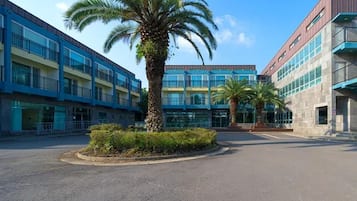 A multi-story building with a central courtyard, palm trees, and a clear sky.