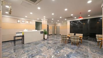 A hotel lobby with a reception desk, seating area, and a fireplace.