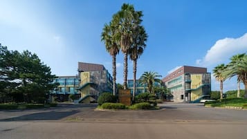 A building with a modern design, featuring a central staircase and palm trees in the foreground.