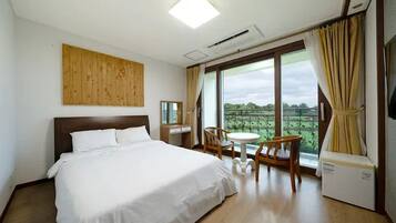 Une chambre d’hôtel avec un grand lit, un bureau, une chaise et une vue sur l’extérieur.