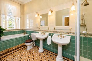 Un baño con bañera, dos lavamanos, inodoro y ducha.