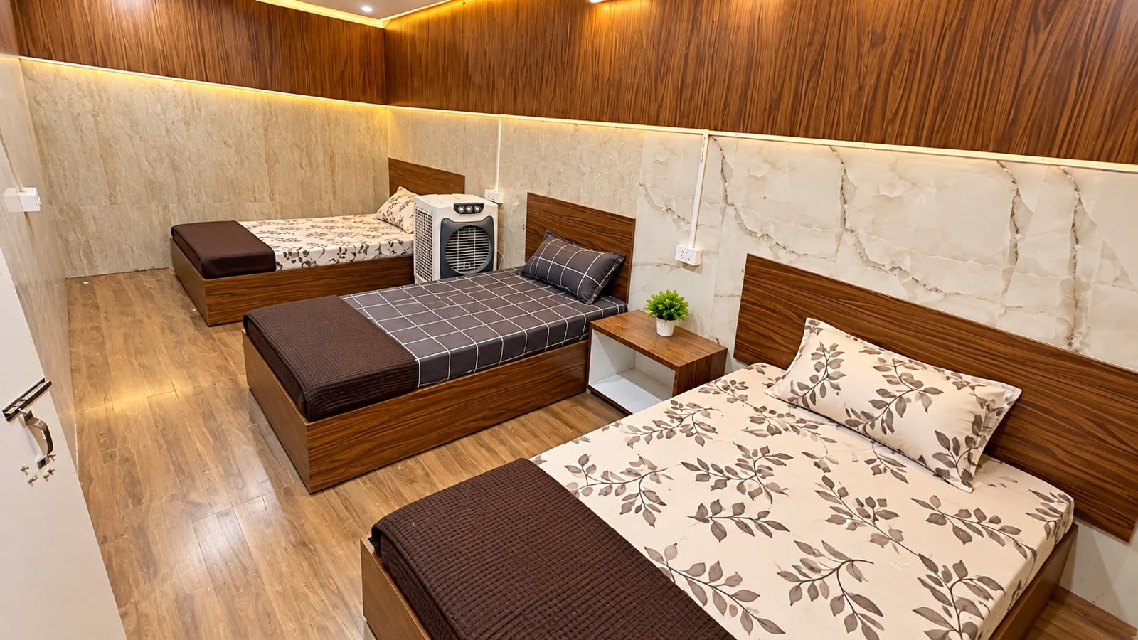 Een compacte hotelkamer met een bed, een slaapbank, een klein tafeltje en een wandheater.