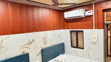 A hotel room with two beds, a ceiling fan, an air conditioning unit, and a marble-patterned wall.