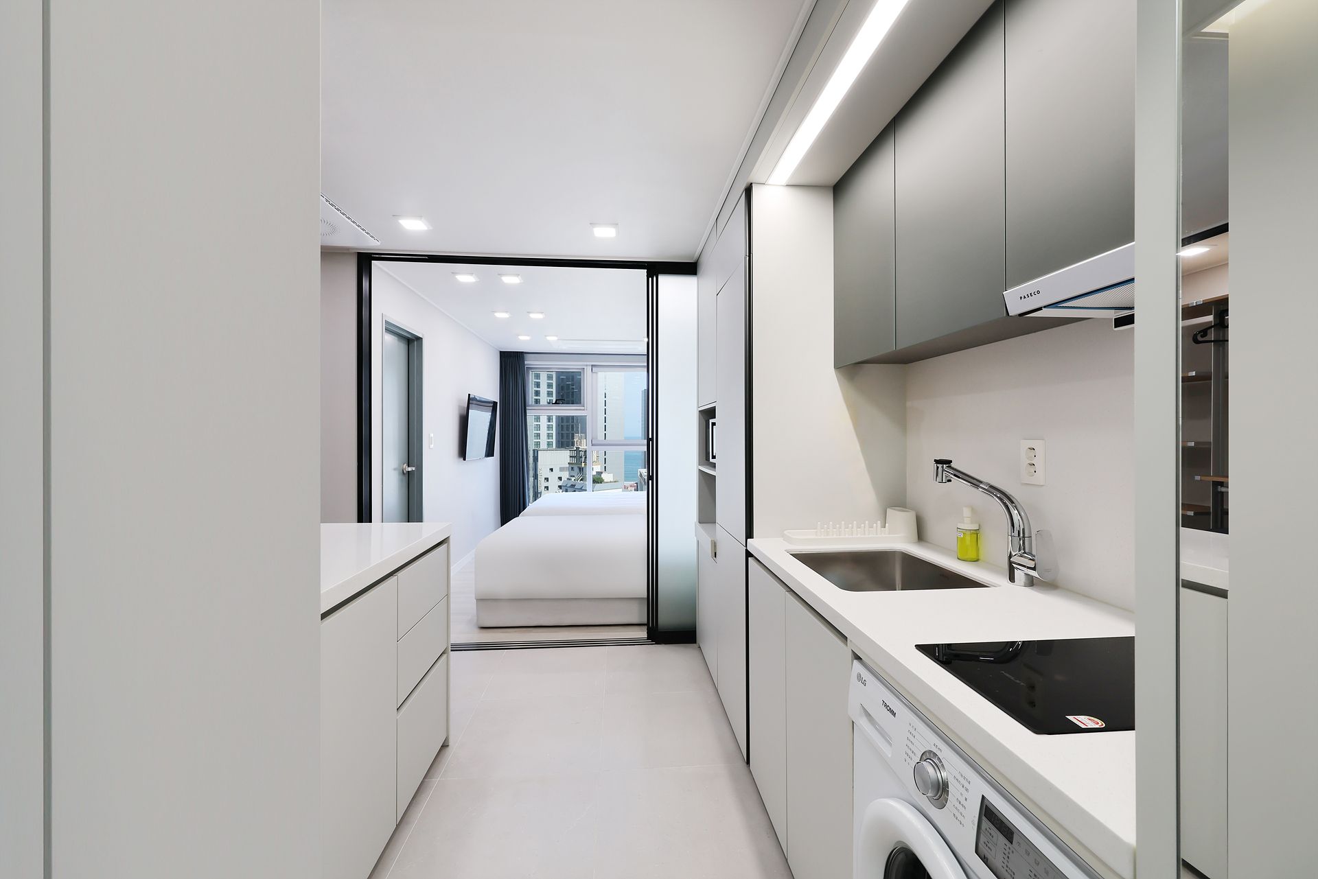 Una cocina moderna con lavadora, un lavamanos y vistas a la ciudad.