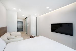 A modern hotel room with a large bed, a flat-screen TV mounted on the wall, and a sliding door leading to a bathroom. - Avenue The Solid (Busan)