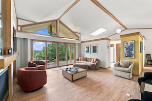 Un vaste espace de vie doté d’un haut plafond, d’un plancher en bois, d’une grande porte-fenêtre coulissante donnant sur une terrasse extérieure et d’un coin salon confortable.